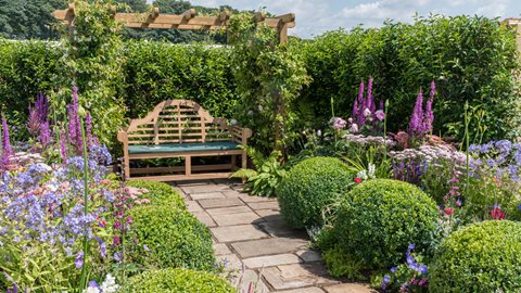This charming garden follows a traditional Edwardian theme, with its twin lavishly planted borders, pergola and Lutyens-style bench