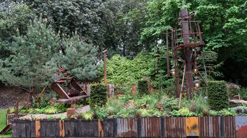 Depicting an industrial space that is being reclaimed by nature, rusting structures from an abandoned quarry are being overtaken by colourful plantings of geum, digitalis and Candelabra primulas