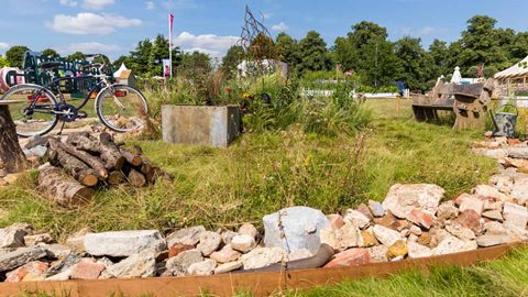 The concrete and brick rubble on the perimeter contrasts with the area of long grass and wildflowers placed to support wildlife along with a simple stack of logs.