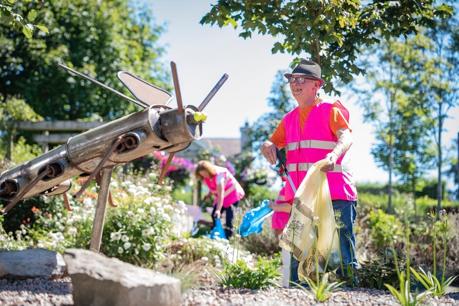 A community gardener picks up litter in a garden