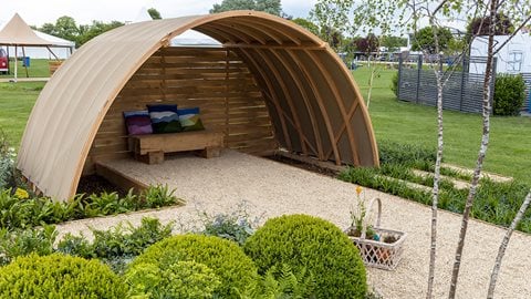 With a curved wooden shelter and central gravel area, this garden offers lots of space for entertaining and relaxing.