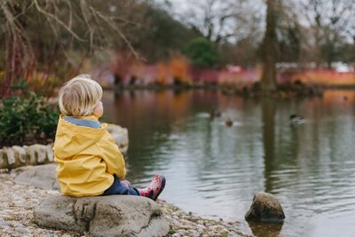 little boy sitting by a lake