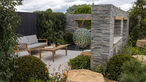 Low dividing walls punctuated with viewing 'windows' allow glimpses through to other areas. Pines, irises, pittosporums and rosemary give the planting a Mediterranean feel.