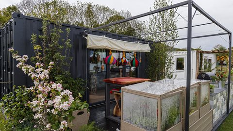 Edible plants surround the outdoor entertaining space, with tomatoes and peppers growing in boxes at the front of the garden