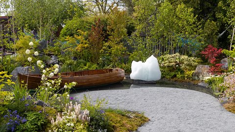 Mixed borders featuring <i>Ceanothus</i>, hostas, <i>Tiarella</i> and sage surround the central lake on which a boat floats beside an ice sculpture, creating a living art installation