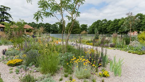 This walk-through garden features informal borders of calming natural hues that sit within a sweeping path of gravel