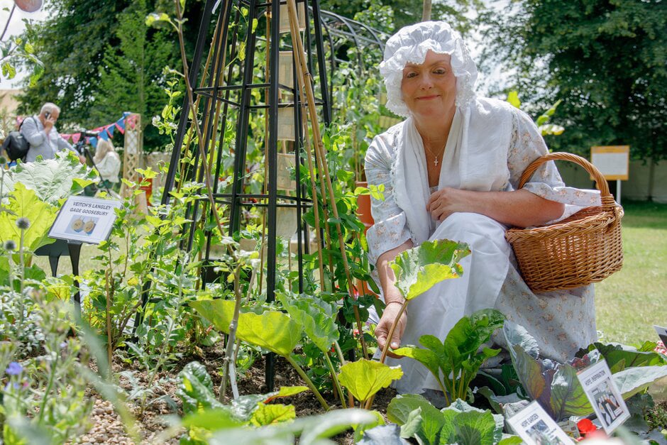 Angela Parton poses in traditional costume on the Feltham Firsts and Greats community allotment at RHS Hampton Court Palace Garden Festival