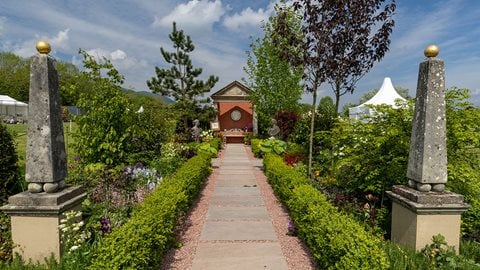 A formal design, gardened informally with romantic beds of herbs, shrubs and soft topiary balls framing the path leading to the majestic Victoria and Albert Temple