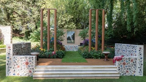 Two sets of stumps dominate the foreground, with tall willows - the wood used to make cricket bats, towards the rear. The planting features an iconic Indian species, blue <i>Meconopsis</i> poppies.