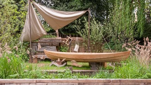 This garden captures a scene from the Norfolk Broads with a plant filled waterway and jetty on which stands a replica of a 900 year old boat.