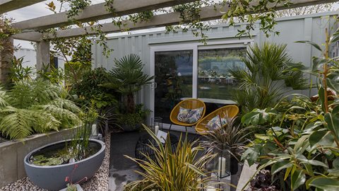 The lush tropical planting contrasts with the concrete elements of the garden, showing how urban spaces can be transformed with plants