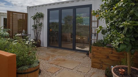 Raised planters and pots of edibles surround a gravelled patio area