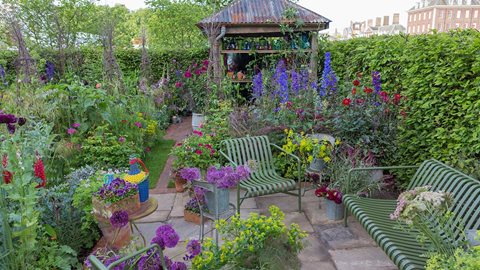 The secluded seating area is next to a shed in which to arrange the freshly cut flowers from the garden - there's even a colourful selection of vases inside.