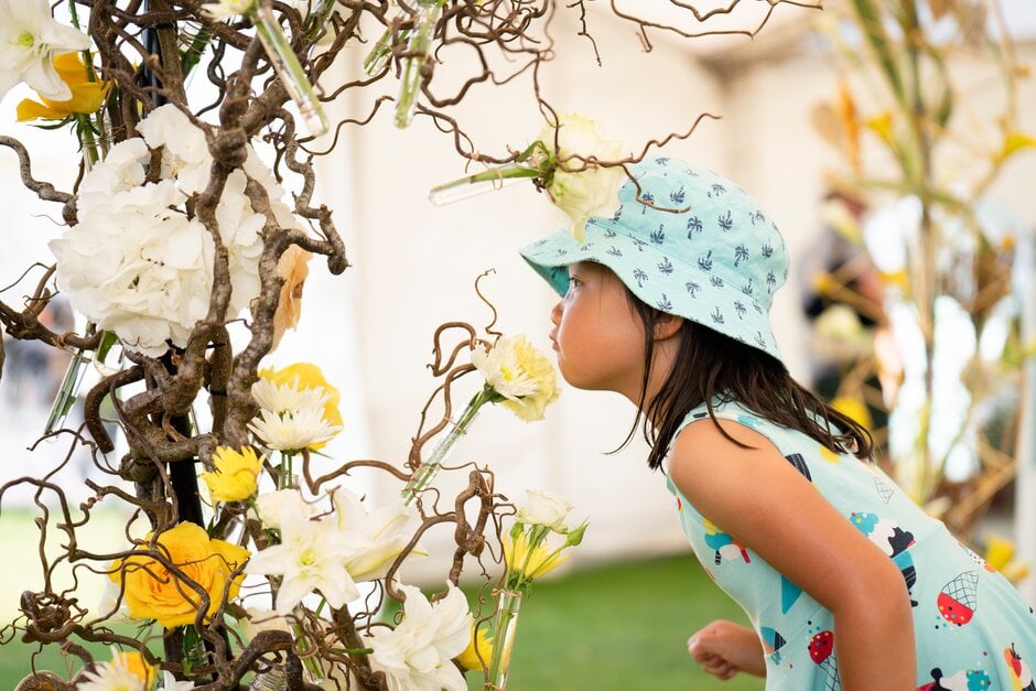 Child smells a flower at RHS Tatton Park 2022
