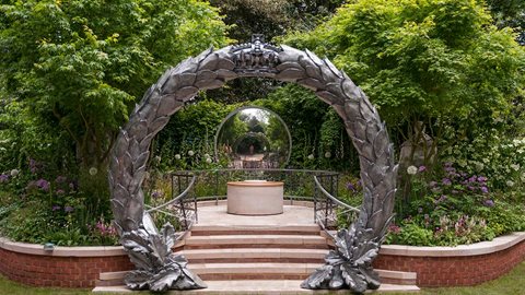 The garden is entered via an ornamental gateway up a flight of steps to a central paved area. Lavish planting including multi-stemmed acers and drifts of alliums provide an immersive feel.