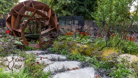 Vibrant red and orange Helenium are mixed with flaming dahlia, scarlet cosmos, and Tibettan Cherry, exhibiting it's characteristic peeling bark symbolizing the scorching from the meteors arrival