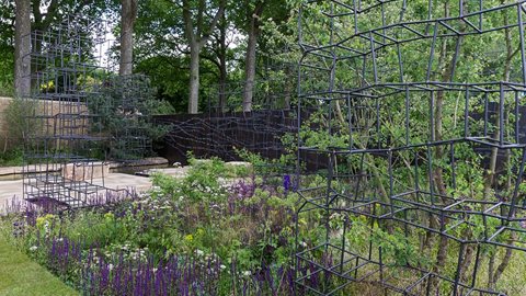 Diagonal view into the garden shows the series of open frameworks rising from soft planting of valerian, salvia, Stipa gigantea and other perennials