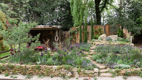 A lean-to shelter, perhaps for visiting donkey, overlooks a central well and a terraced garden of silver and purple drought-tolerant Mediterranean-style plants