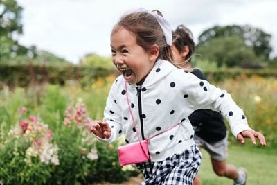 Child laughing running through garden
