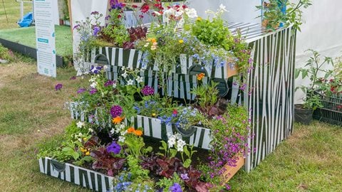 A three-tiered planter made from pallets and decorated in an eye-catching style.