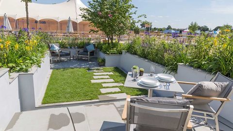 A patio in sun overlooks the sunken grass area, which is surrounded by raised beds fed by rainwater and planted with both bog plants and more drought tolerant plants where the water supply is scarcer.